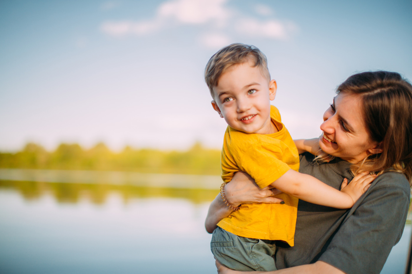 Kleiner Junge auf dem Arm der Mutter am See