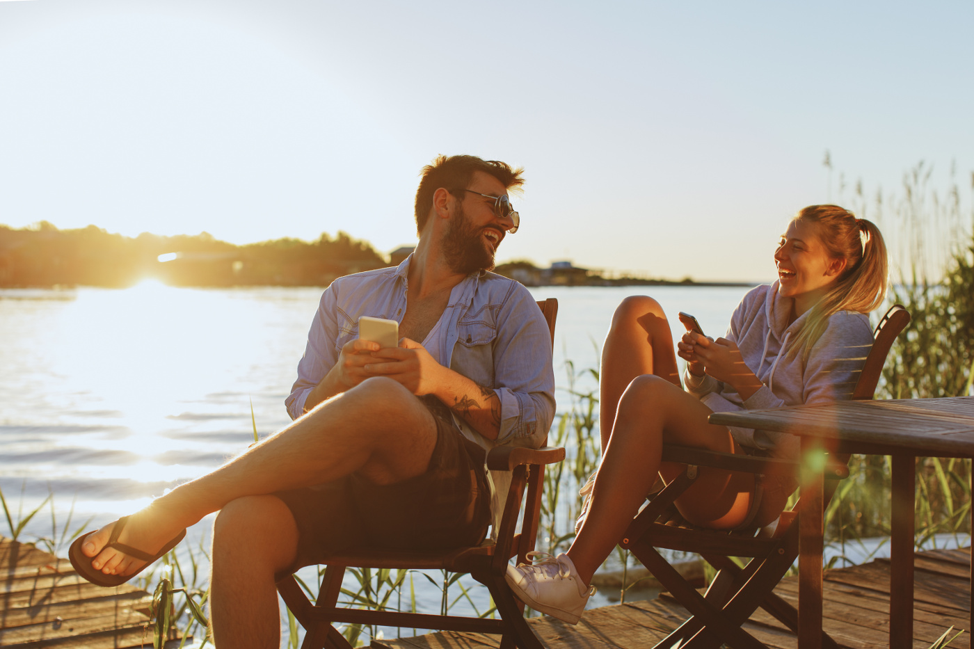 Startseite - Sommer Zwei junge Erwachsene lachen zusammen in der Abendsonne am See