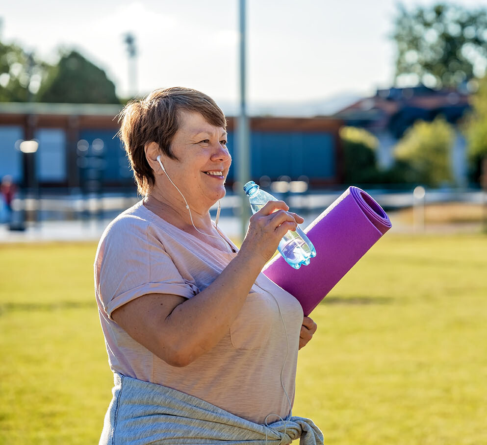Frau mit einer Yogamatte und Wasser