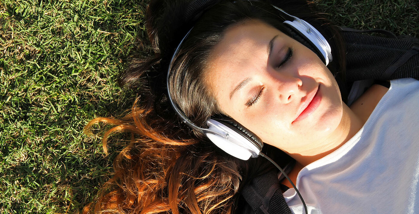 Frau hört entspannt auf der Wiese Musik