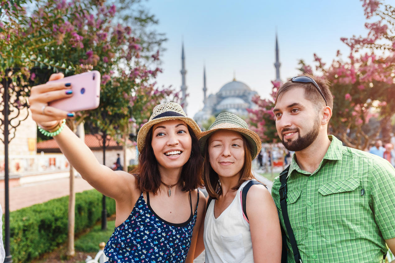3 Freunde machen ein Selfie vor einer Moschee und sind gut abgesichert mit dem Auslandskrankenschein
