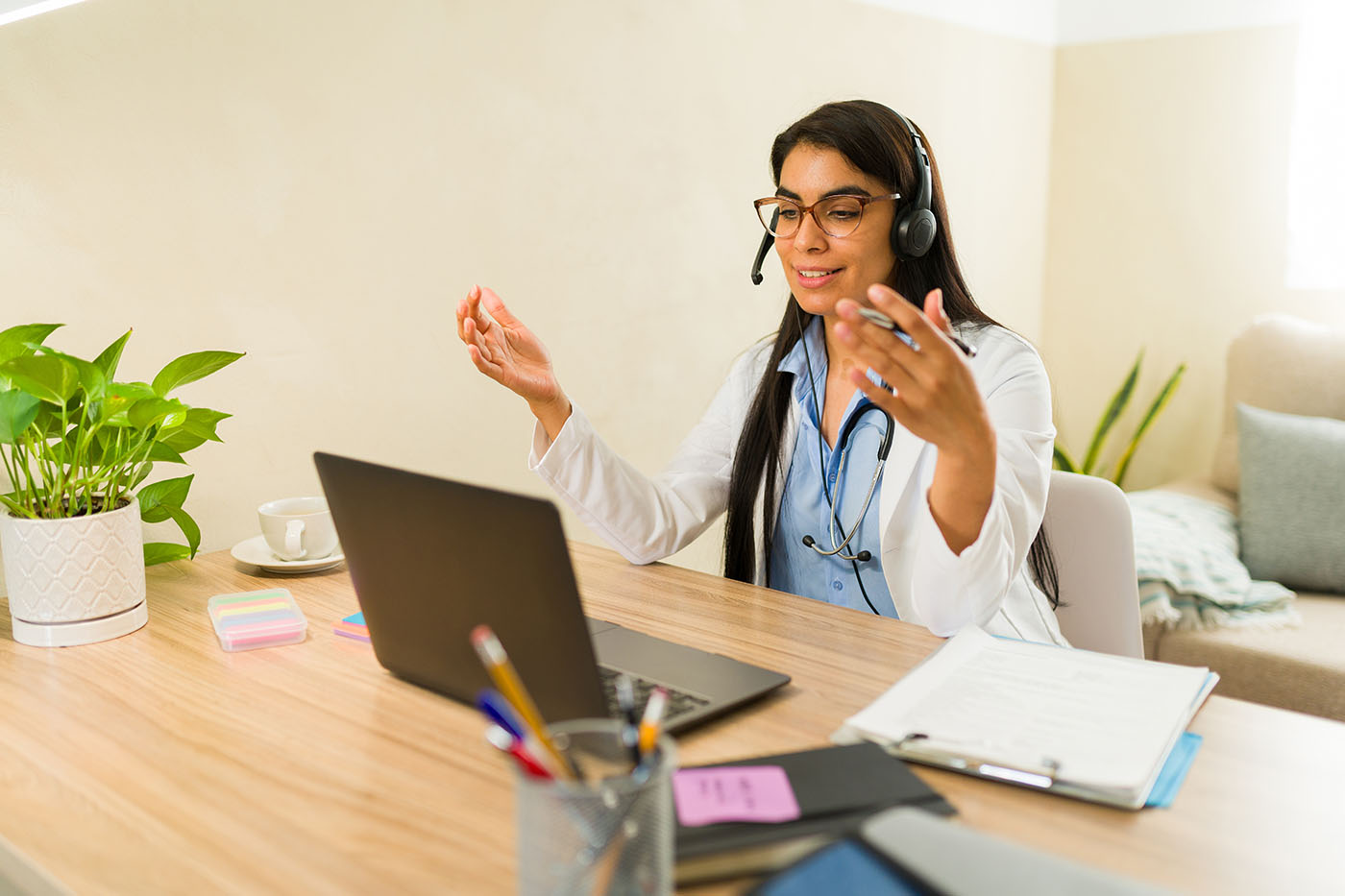 Ärztin telefoniert mit Headset und schaut in einen PC.
