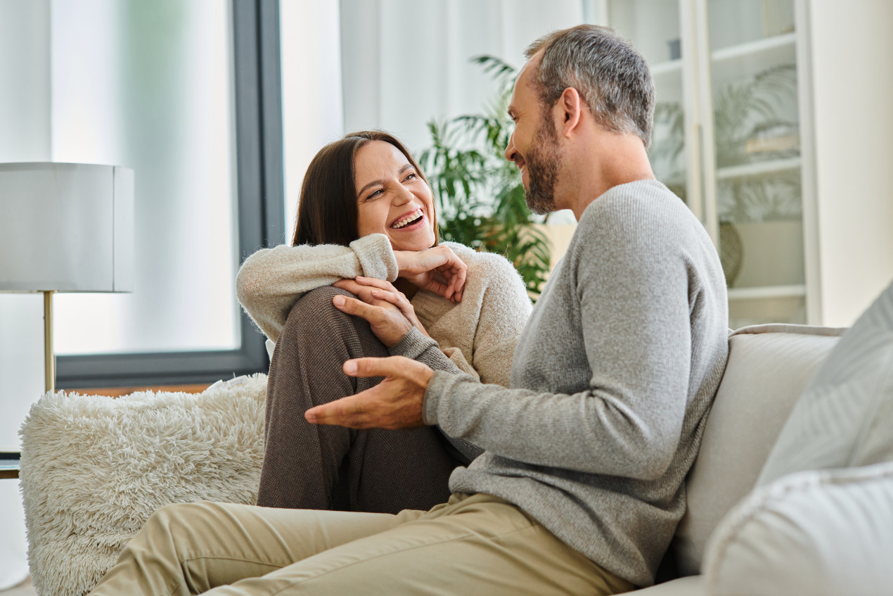 Paar sitzt auf Sofa: Ehepartner können familienversichert sein, wenn sie kein eigenes Einkommen haben.