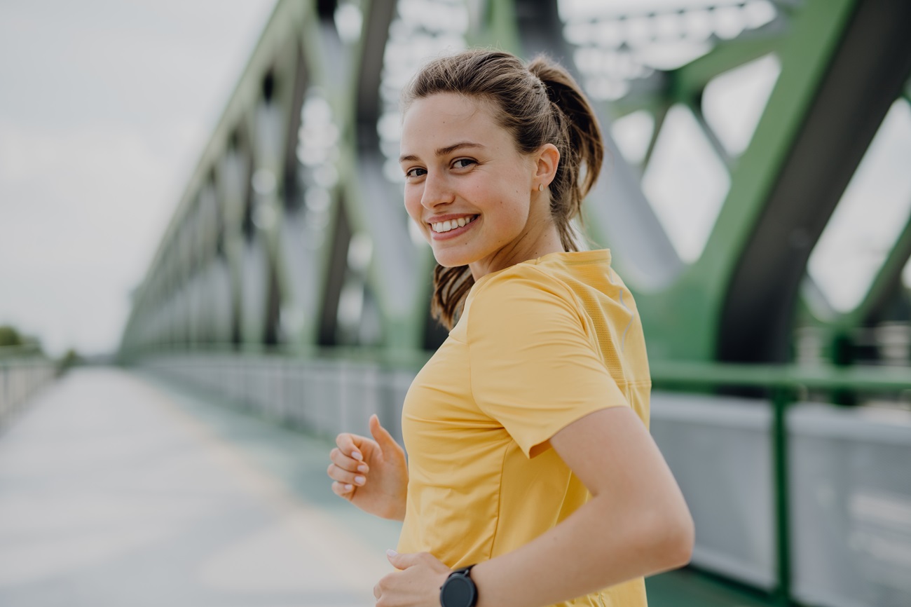 Junge Frau joggt über eine Brücke