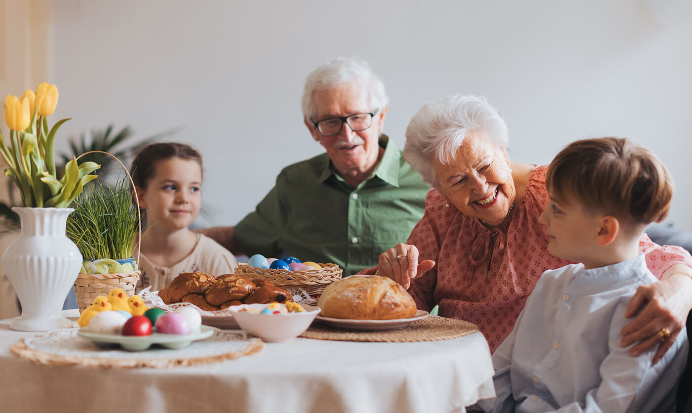 Großeltern sitzen an Ostern mit ihren Enkeln am Tisch