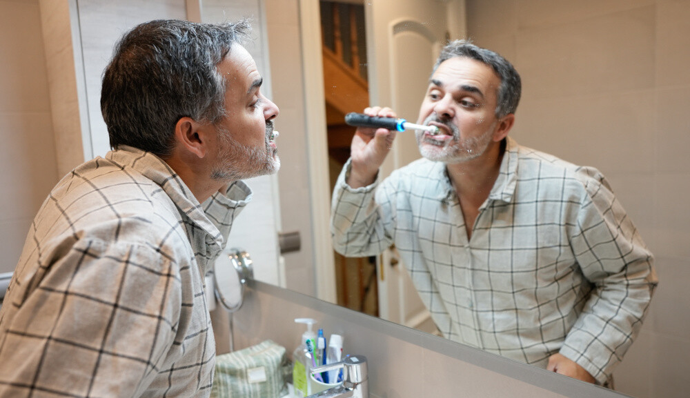 Mann putzt seine Zähne mit einer elektrischen Zahnbürste