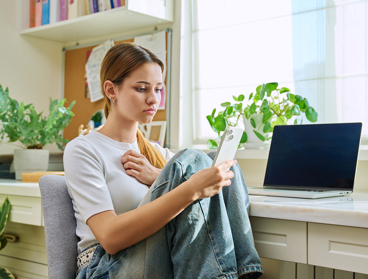Jugendliche schaut traurig in ihr Smartphone