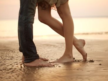 Junges Paar steht barfuß am Strand