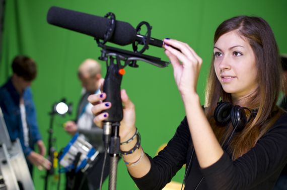 Junge Frau mit Mikrophon vor einem Greenscreen