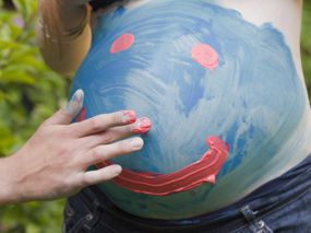 Mann malt seiner schwangeren Freundin den Bauch an