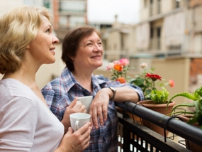 Zwei Frauen genießen eine Tasse Kaffee auf dem Balkon