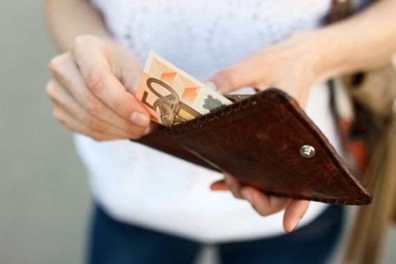 Frau steckt Geld in ein Portemonnaie
