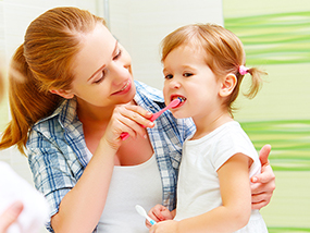 Mutter putzt bei ihrer Tochter die Zähne