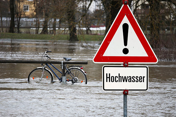 überflutete Straße mit Hochwasser-Warnschild
